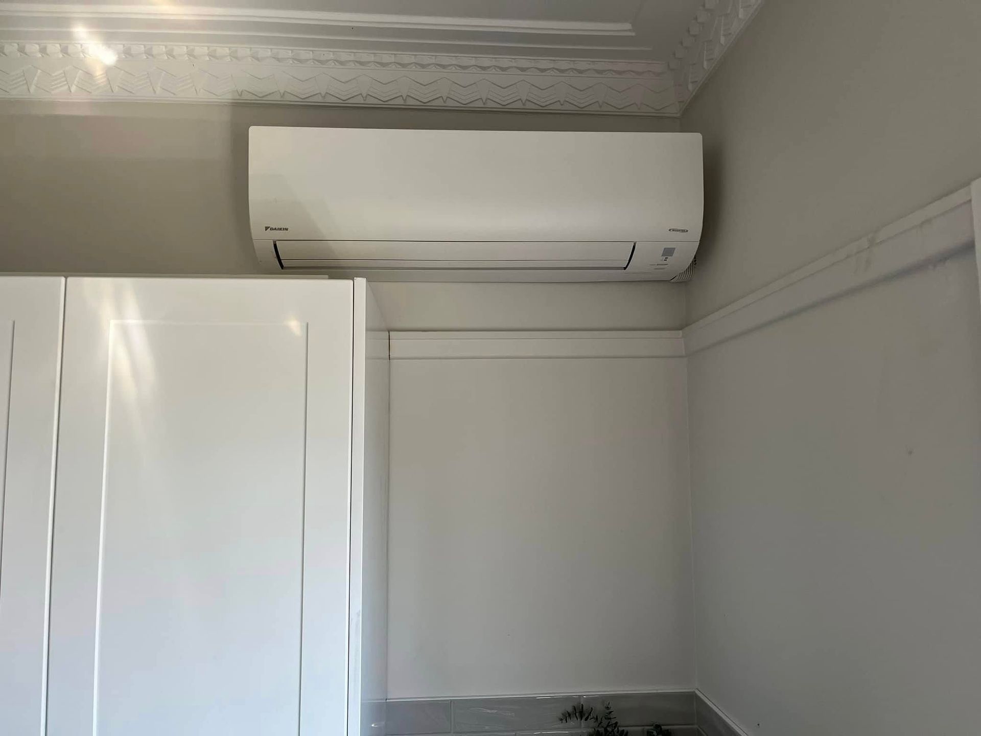 A White Wall-mounted Air Conditioner Unit Installed Above a White Cabinet — OHMY Electrical Contractors in Camp Hill, QLD