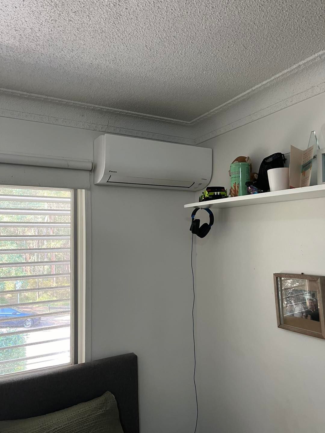 A Wall-mounted White Air Conditioner is Positioned Above a Window and a Shelf — OHMY Electrical Contractors in Camp Hill, QLD