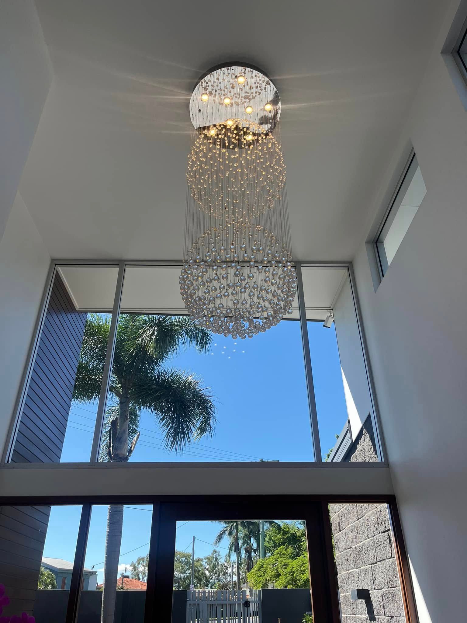 A Tall, Tiered Crystal Chandelier Hangs From a Ceiling in an Entryway — OHMY Electrical Contractors in Mount Gravatt, QLD