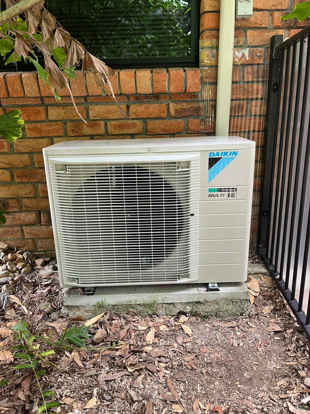 A Beige Daikin Outdoor Air Conditioning Unit Sits on a Concrete Slab — OHMY Electrical Contractors in Bulimba, QLD