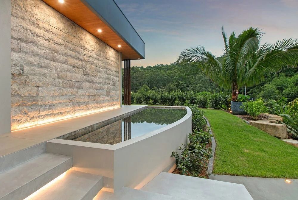 A Modern Home With a Stone Wall and Glowing Lighting — OHMY Electrical Contractors in Carina, QLD