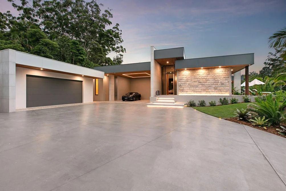 A Modern, Single-story Home at Dusk With a Large Concrete Driveway — OHMY Electrical Contractors in Carina, QLD