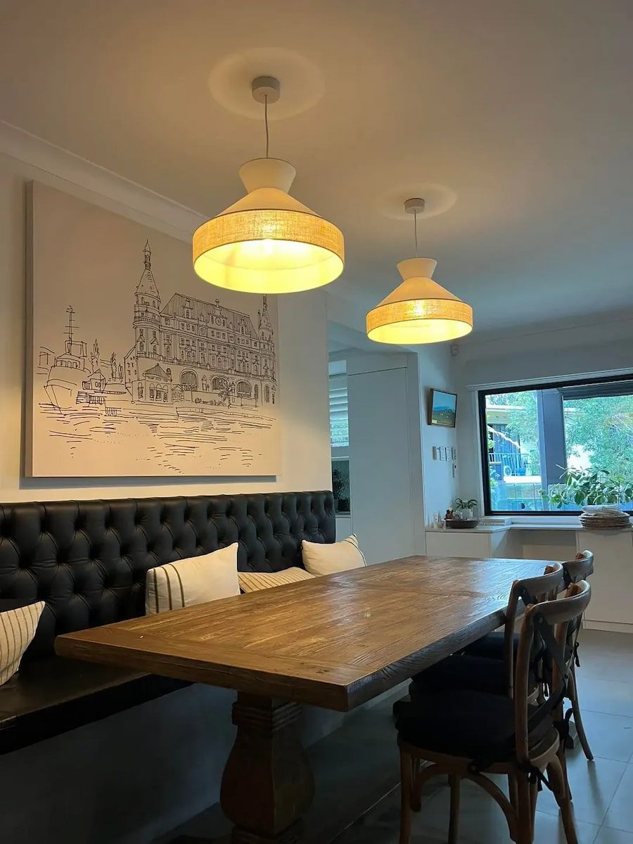 Cozy Dining Room With Wooden Table, Tufted Bench and Pendant Lights — OHMY Electrical Contractors in Carina, QLD