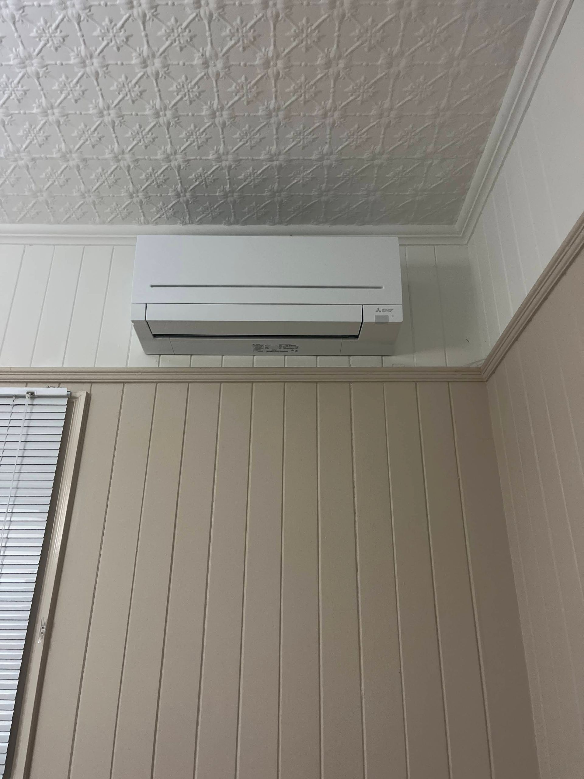 A White Wall-mounted AC Unit Installed Near a Patterned White Ceiling — OHMY Electrical Contractors in Carina, QLD