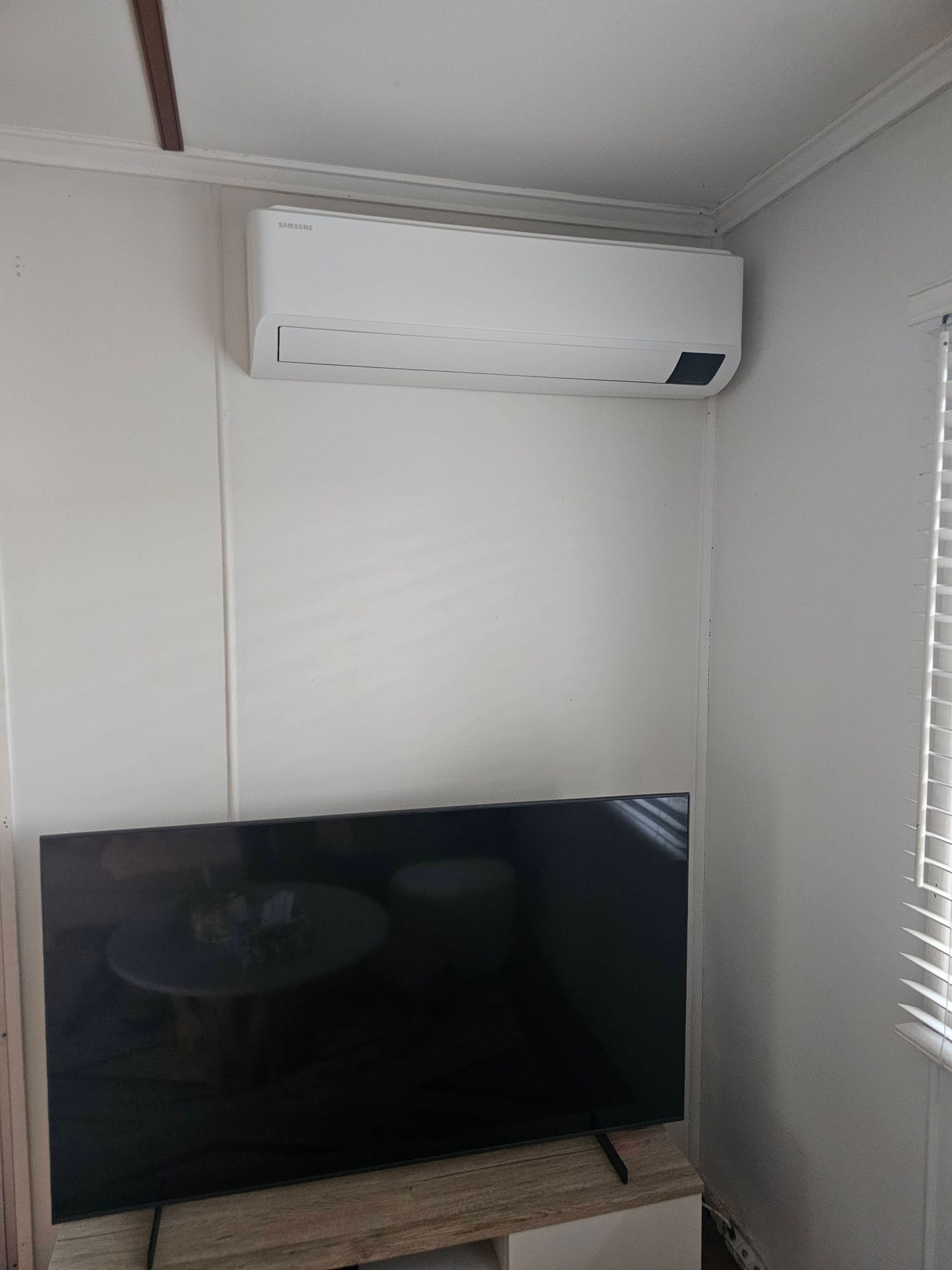 A Wall-mounted AC Positioned Above a Flat-screen Television in a Room — OHMY Electrical Contractors in Mount Gravatt, QLD
