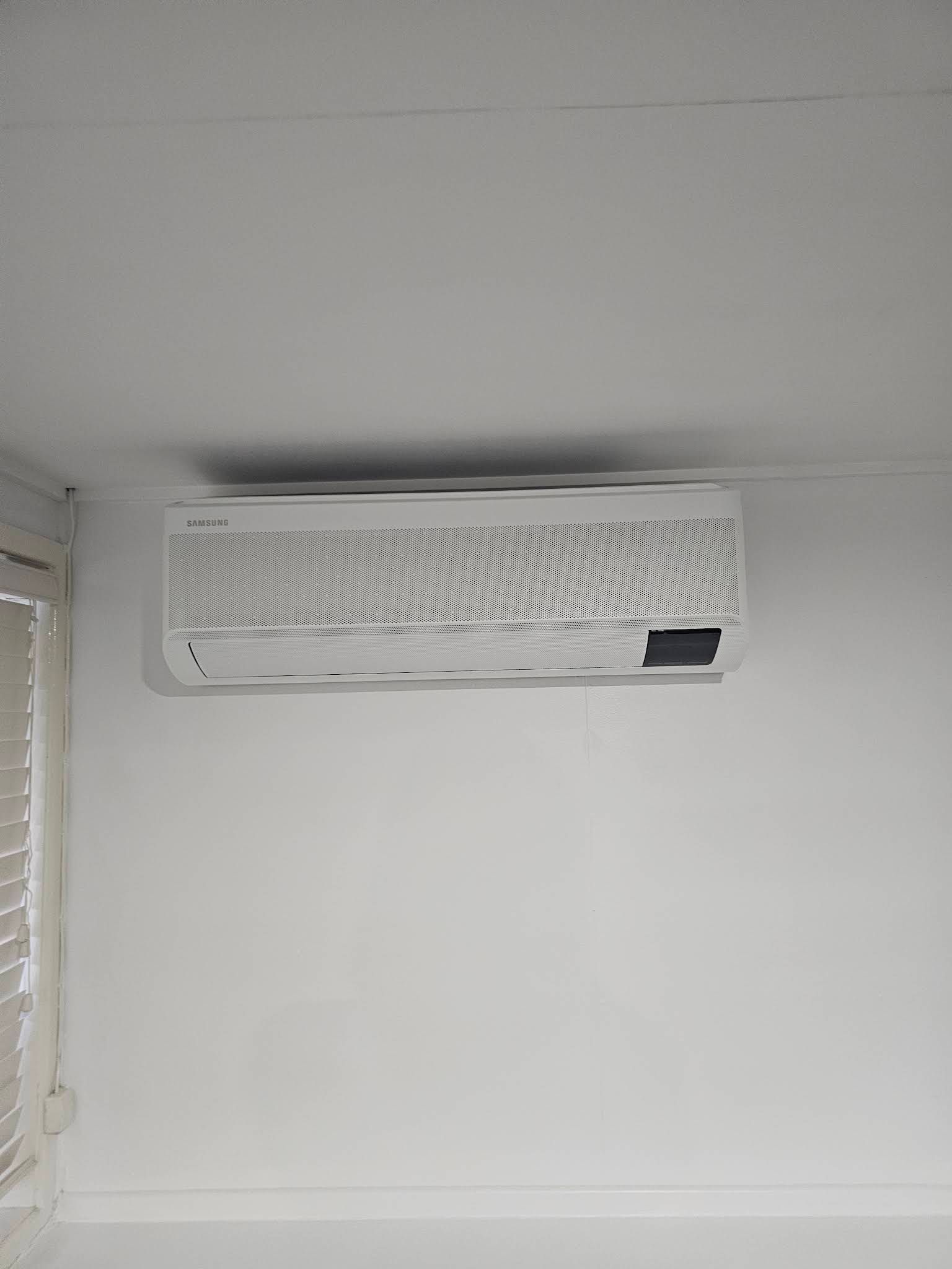 A White Wall-mounted Air Conditioner Unit is Installed Near the Ceiling — OHMY Electrical Contractors in Mount Gravatt, QLD