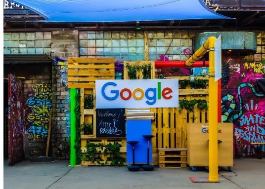 A google sign is hanging on a wall in front of a building.