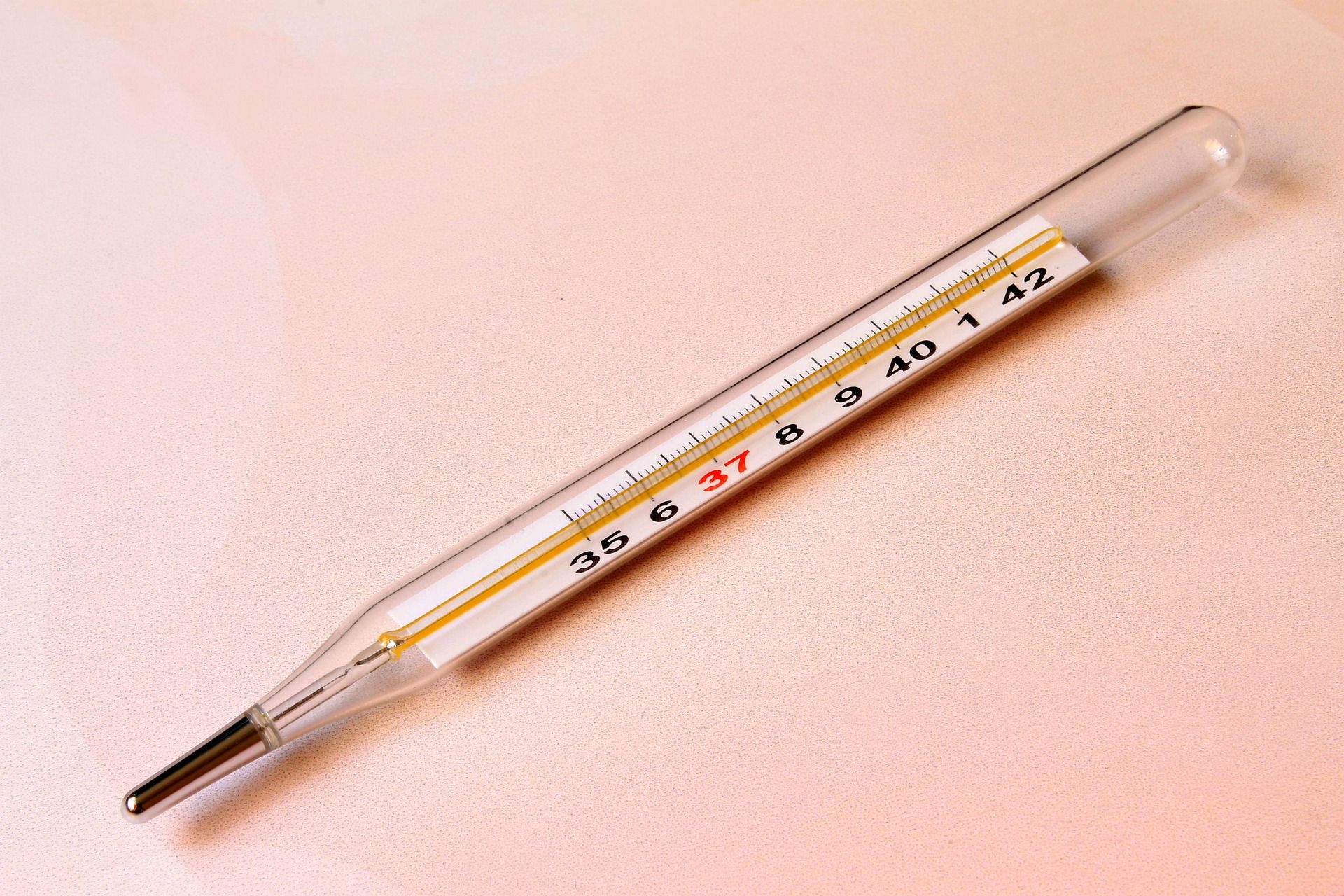 Glazen klinische thermometer op een lichtroze achtergrond