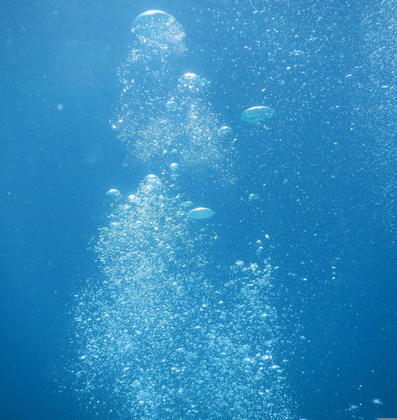 Onderwaterscène met opstijgende bubbels in blauw water.