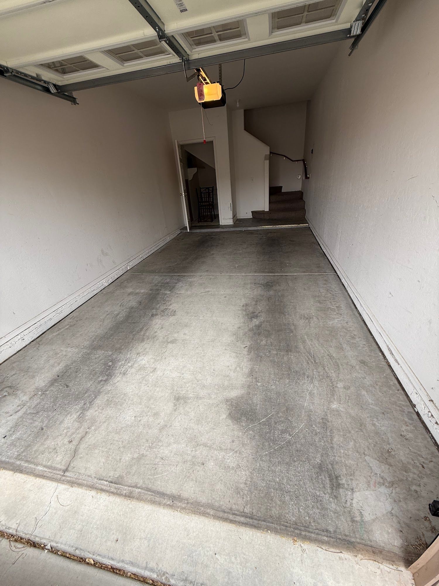 An empty garage with a garage door open and stairs.