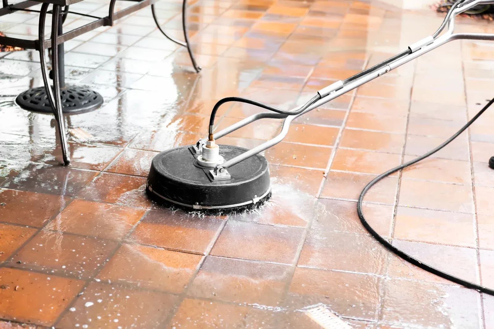 Pressure washer cleaning wet terracotta floor tiles indoors
