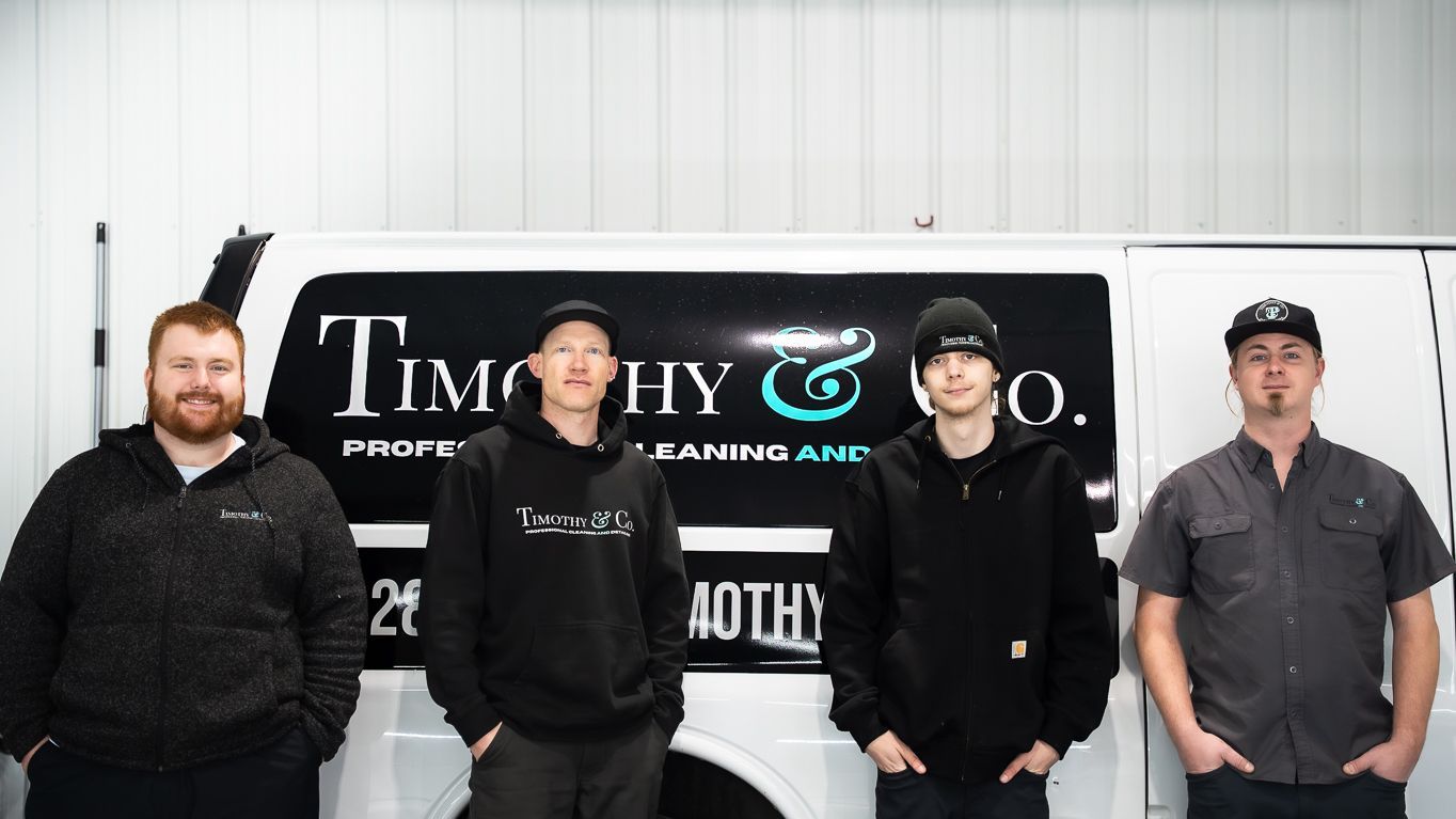 A family is posing for a picture in front of a timothy & co. van.