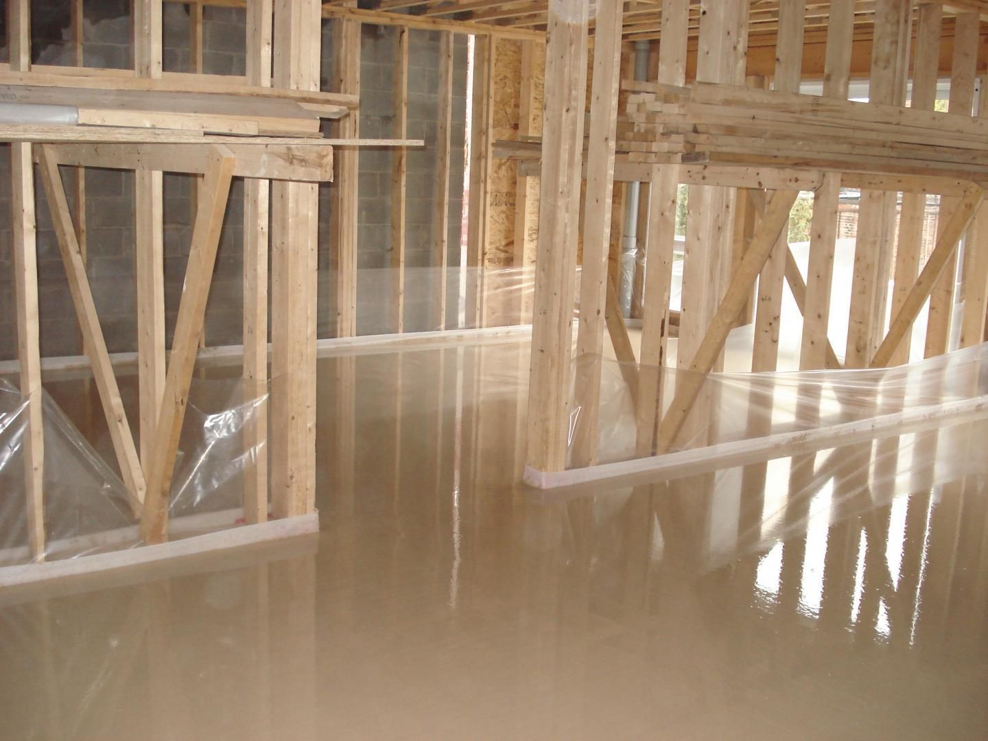 L'intérieur d'un bâtiment en construction avec des poutres en bois et un sol en béton.