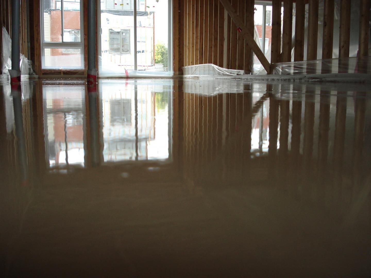 Une pièce avec beaucoup de fenêtres et le reflet d'un bâtiment dans le sol.