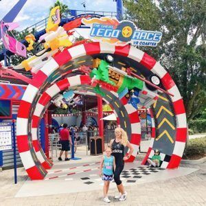 LEGO Race entrance arch with red, black, and white stripes; visitors standing beneath it outdoors.
