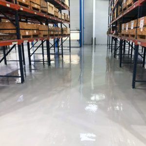 Aisle in a warehouse with shelving on both sides and a shiny concrete floor