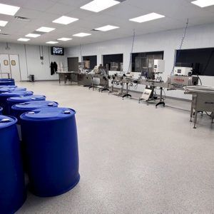 Industrial room with blue barrels in front and rows of stainless steel equipment along the wall