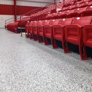 Rows of red stadium seats in an empty indoor arena, viewed from aisle level.