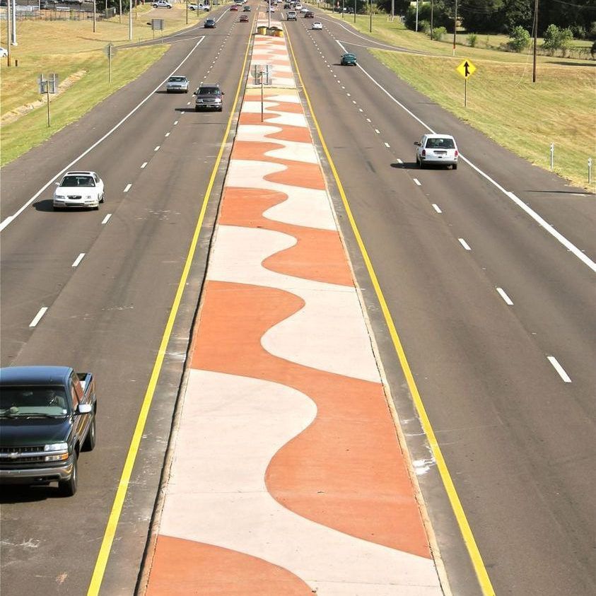 Highway with a painted red-and-white median strip and several cars driving in both directions