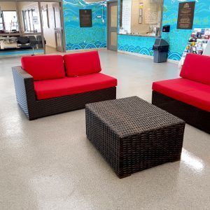 Red wicker lounge chairs and a matching table in a bright indoor lobby area