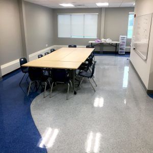 Empty conference room with a long table, black chairs, and window blinds.