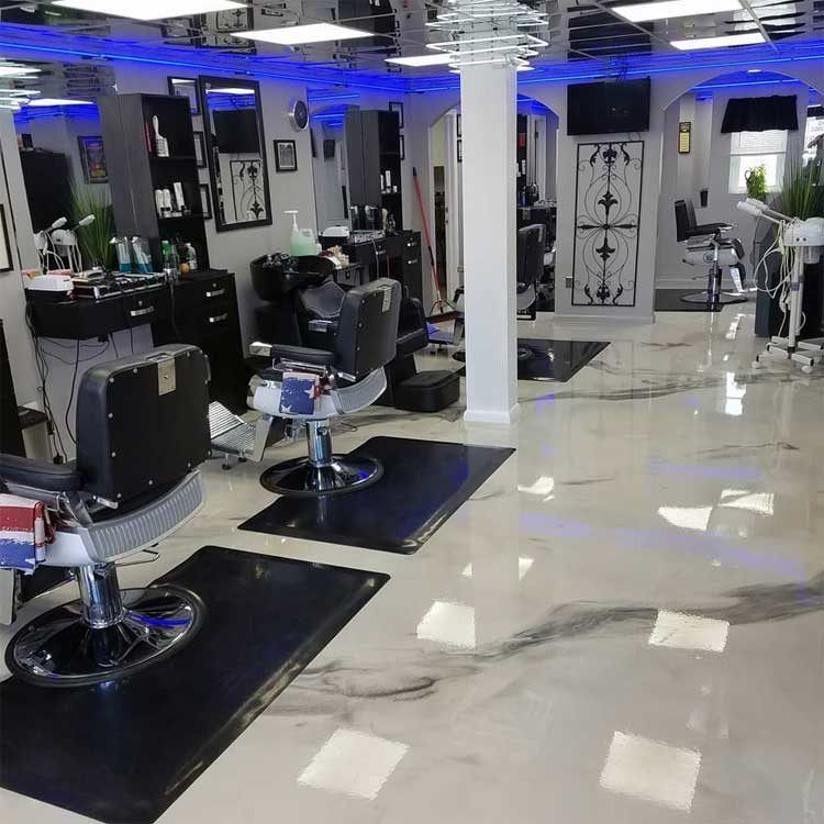 Modern hair salon with black chairs, mirrors, and glossy white floor under blue ceiling lights