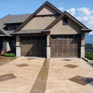 Two-car garage with wooden doors and a tan stone driveway in front of a house