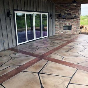 Covered stone patio with sliding glass doors and a stone fireplace wall