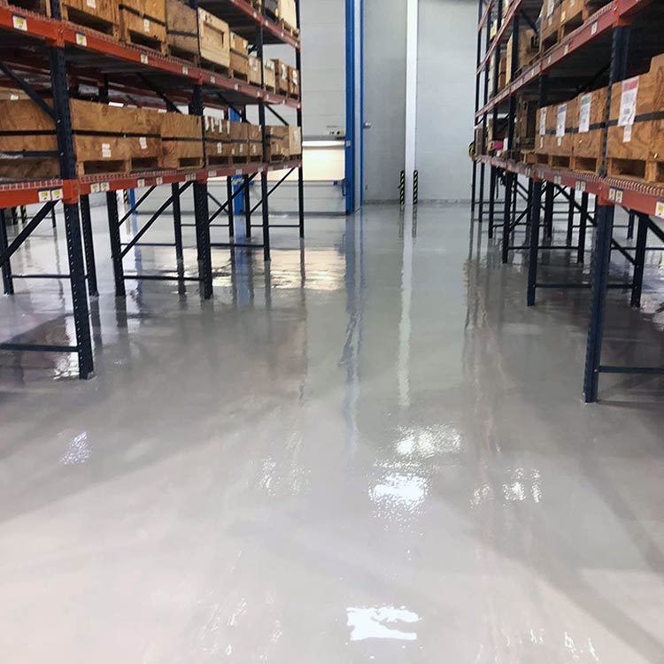 Aisle in a warehouse with metal storage racks and shiny concrete floor.