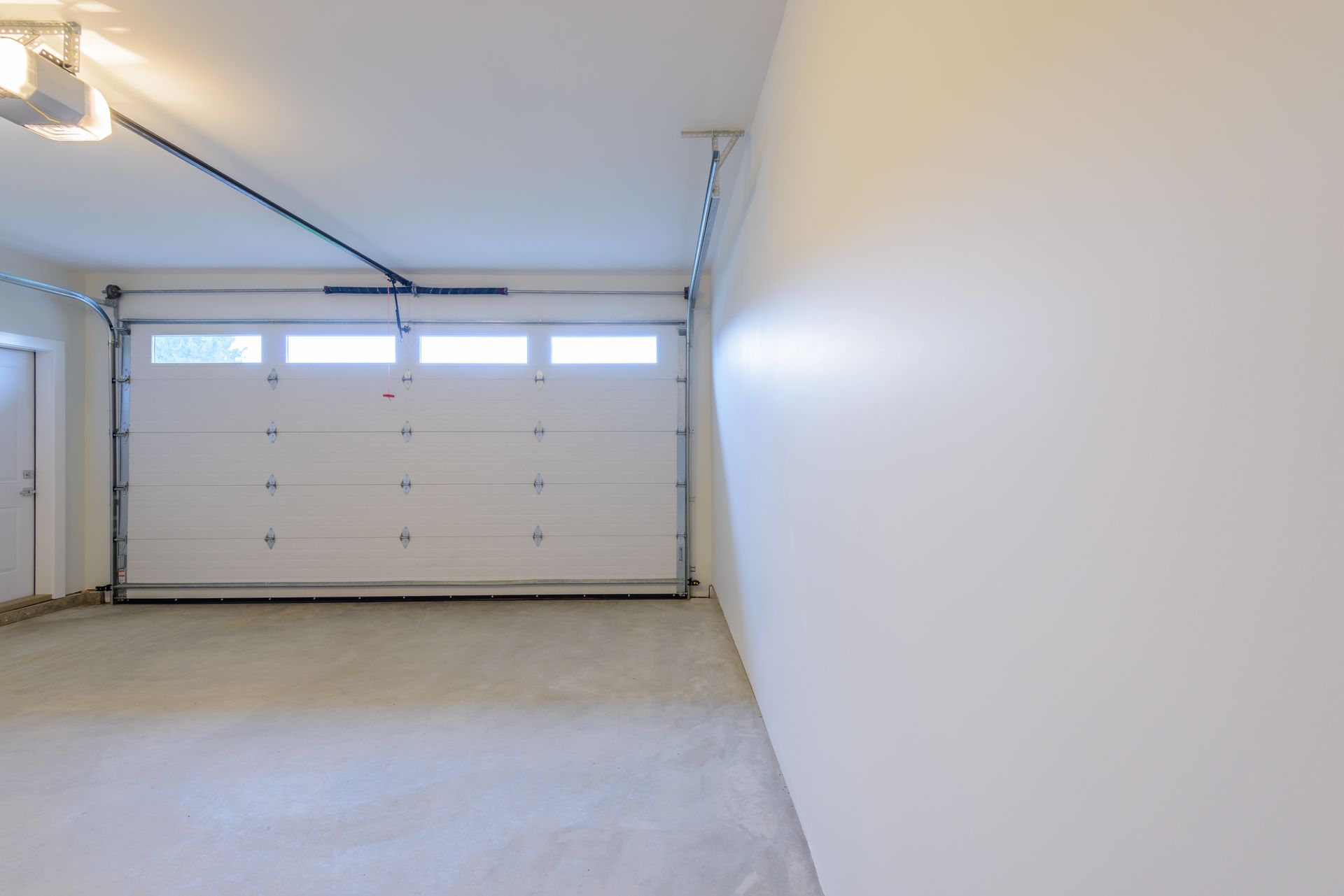 Empty white garage with closed double door and concrete floor