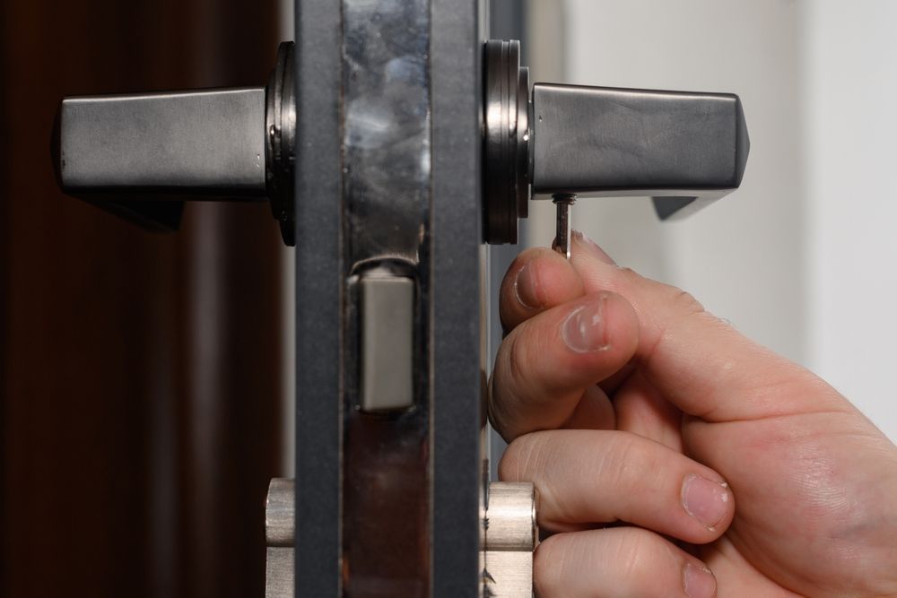 A person is fixing a door lock with a screwdriver.
