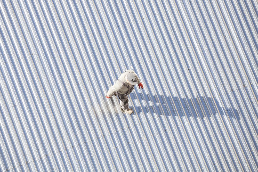 An Aerial View of a Person Standing on a Metal Roof — Apex Roofing Group in Byron Bay, NSW