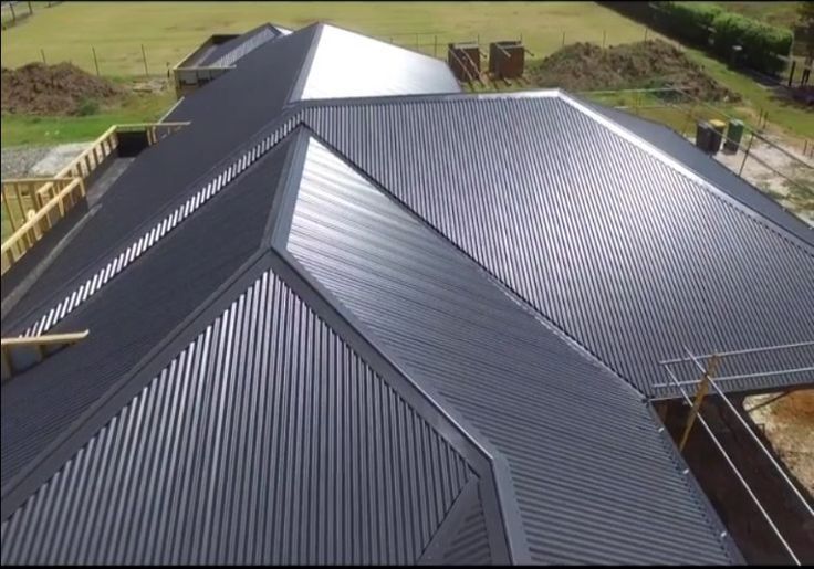 Dark-coloured, complex multi-hipped roof design with clean, sharp ridges and valleys, suited for large homes. — Apex Roofing Group in Byron Bay, NSW