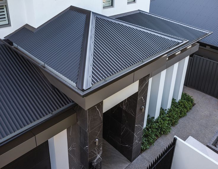 Modern entryway of a residential home with a stylish dark grey corrugated metal roof and sleek black marble columns.— Apex Roofing Group in Byron Bay, NSW