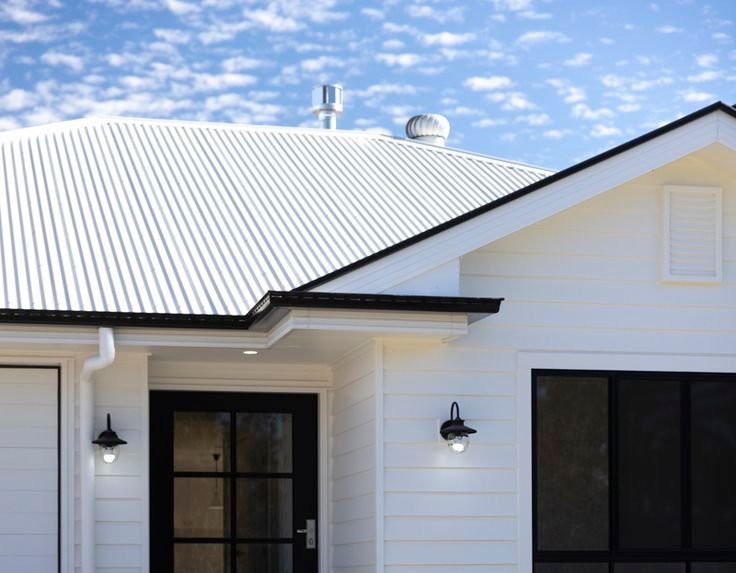 Modern home with white corrugated metal roofing, white weatherboard cladding, black window frames, and a decorative breeze block front fence for a clean, coastal look. — Apex Roofing Group in Mullumbimby, NSW