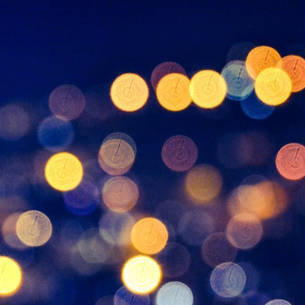 Blurred city lights at night with colorful blue, yellow, and orange bokeh.