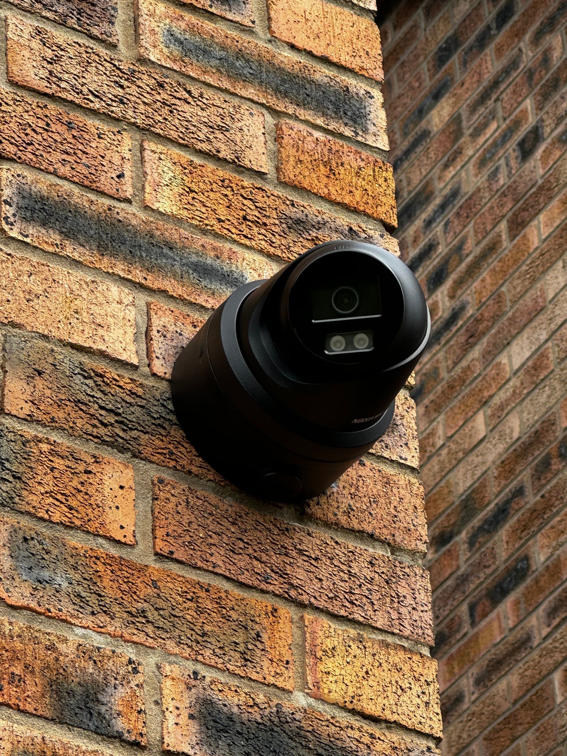 A security camera is mounted on the side of a brick building.