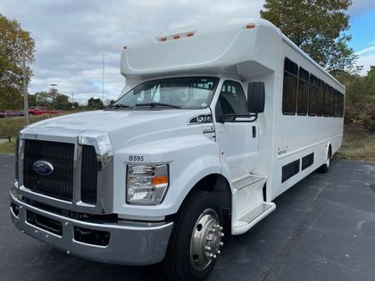 White Ford shuttle bus parked in a lot, angled front view under cloudy skies