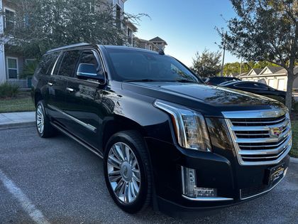 Black Cadillac SUV parked on a street in front of a building, seen in daylight.