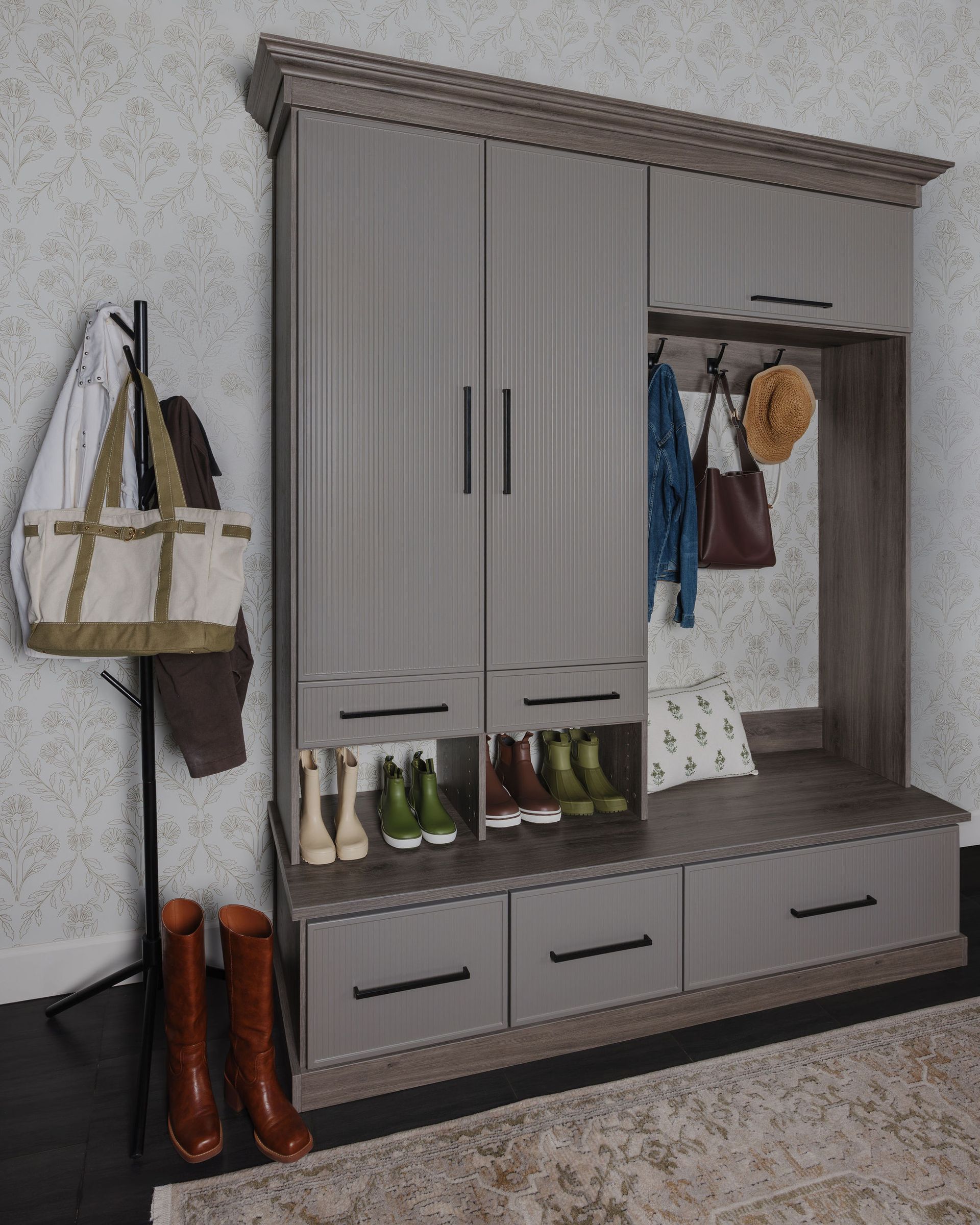 Built-in mudroom with coats, hats, boots, and drawers in a gray interior.