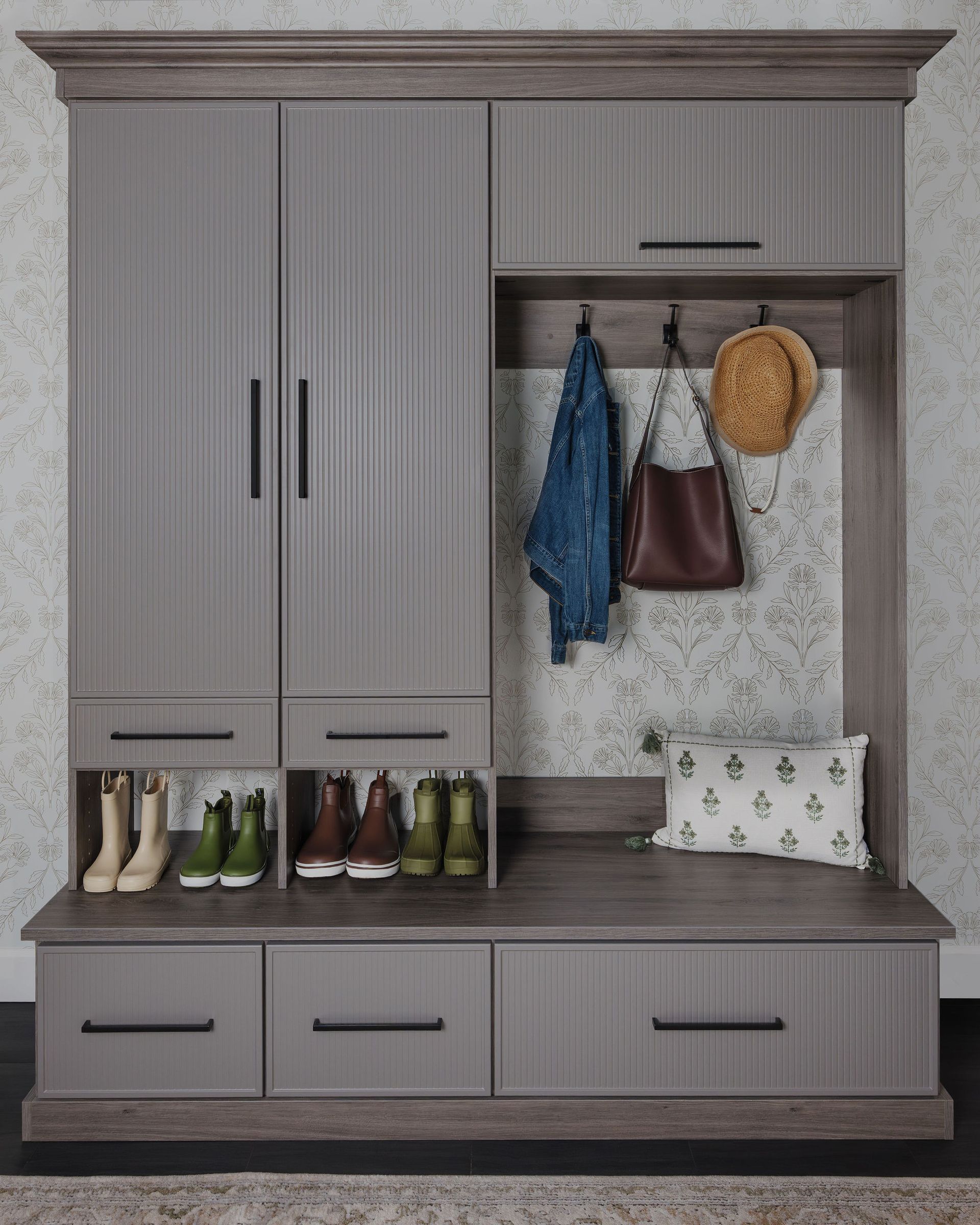 Gray entryway cabinet with bench, shoe storage, hooks, and hanging coats and hat