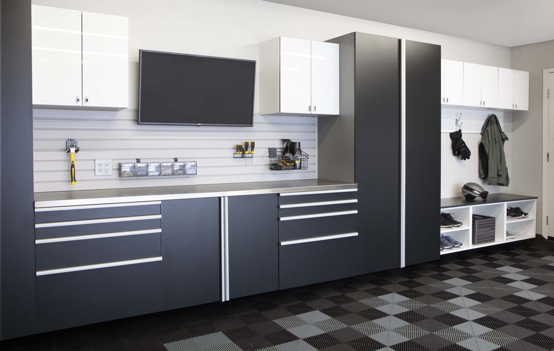 Modern garage with black and white cabinets, wall-mounted TV, and organized storage benches