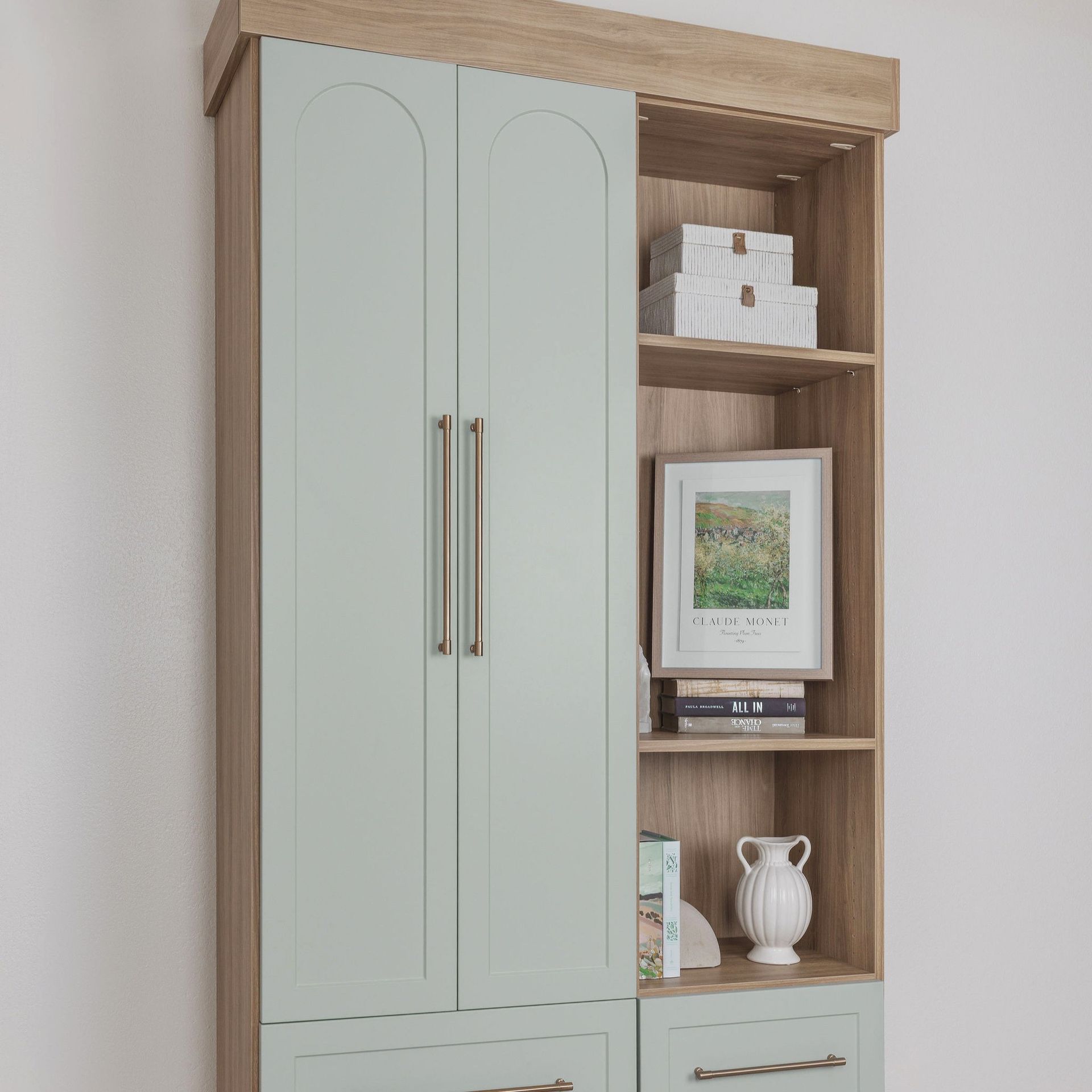 Tall mint cabinet with wood shelving, framed art, books, and a white vase on display