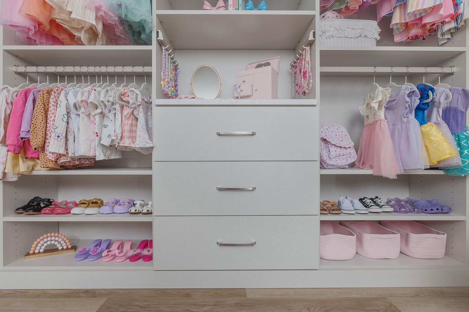 Open closet with shelves, drawers, clothes, toys, and storage bins neatly organized inside.