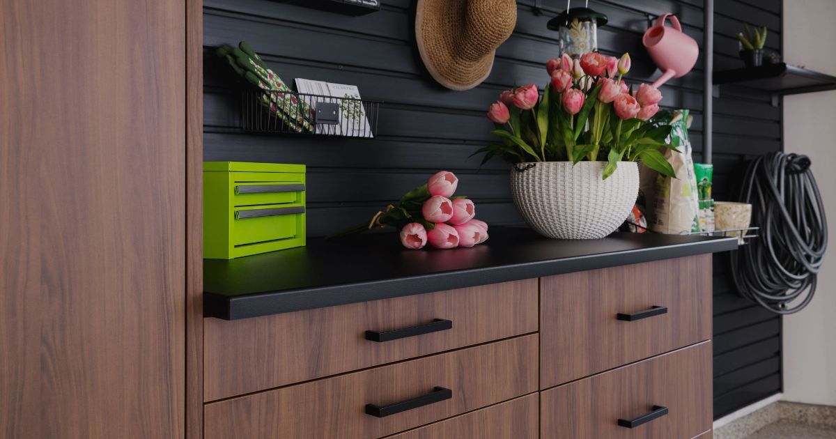 Stylish entryway with dark slatted wall, wood cabinets, green box, pink flowers, and hanging hats and bags
