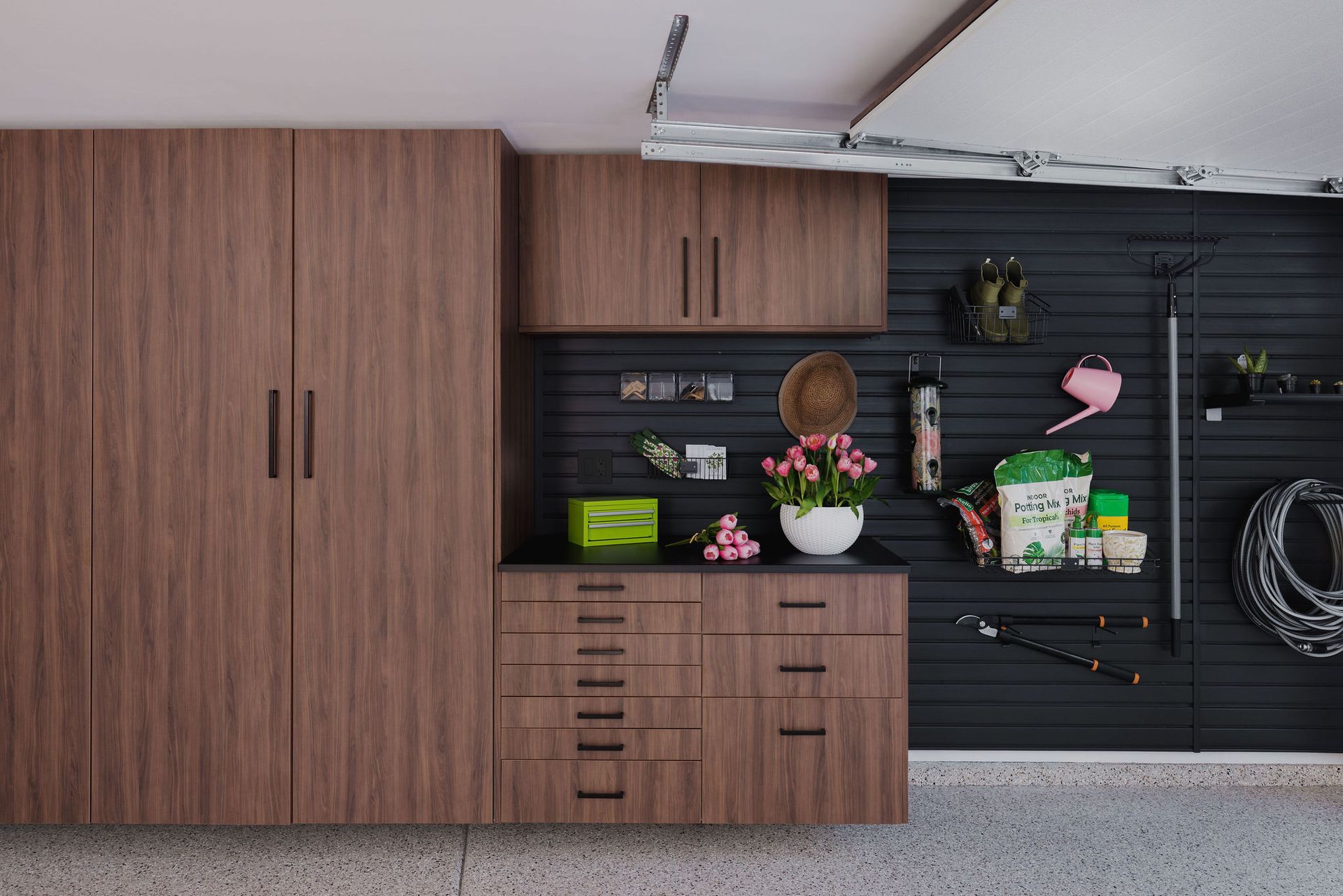 Wooden garage cabinets and black storage wall with gardening tools and decorations