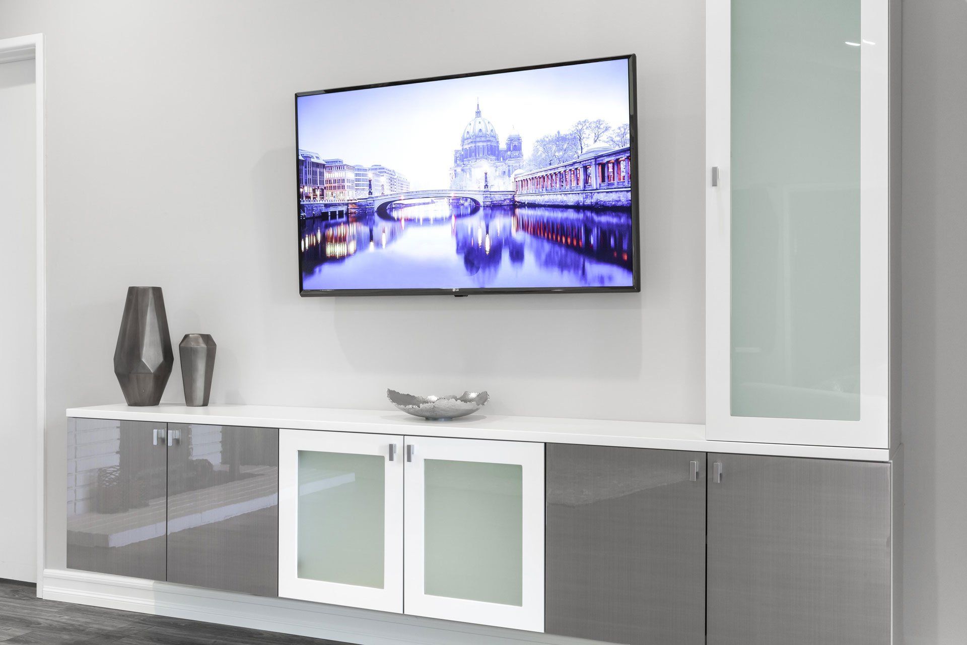 Modern living room with wall-mounted TV above a sleek white media console and decorative vases