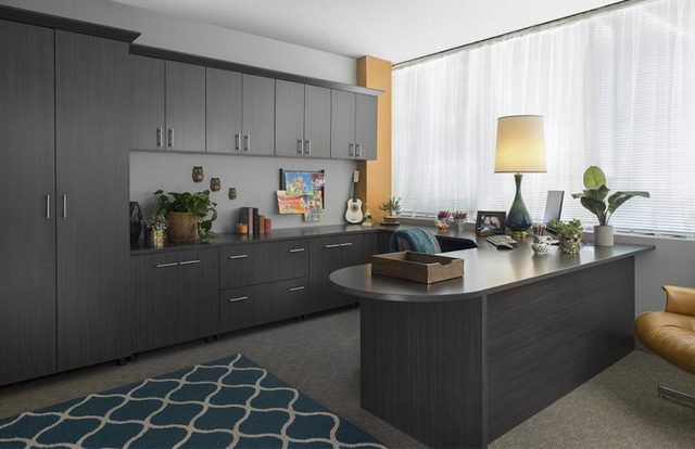 Modern kitchen with dark cabinets, central island, plants, and a large window with a floor lamp nearby