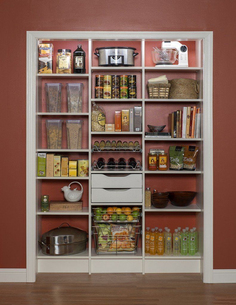 Built-in pantry shelves stocked with canned goods, jars, spices, and kitchen supplies against a red wall