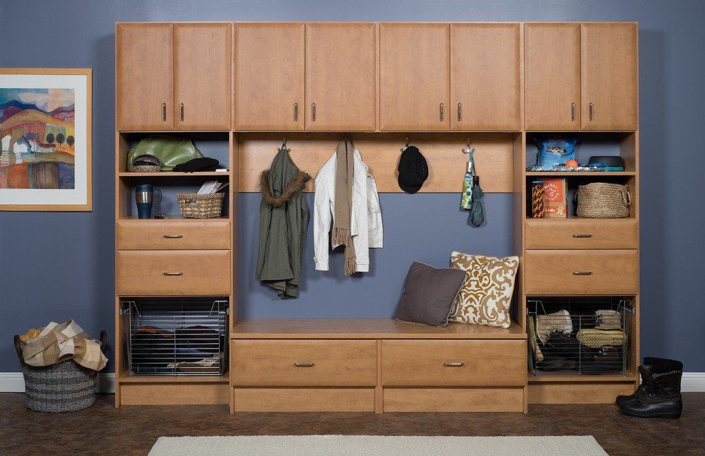 Wooden wall storage unit with cabinets, drawers, shelves, hanging clothes, and a blue bench seat